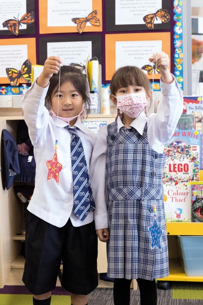 Preparatory students, Jessie and Vita, stand together holding their Matariki star crafts they have made.