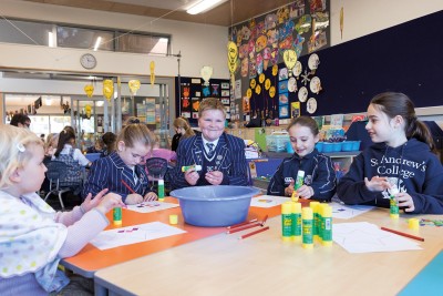 Pre-school student sits at table making Matariki crafts with four Preparatory students.