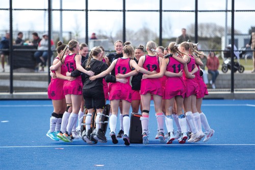 1st XI Girls hockey team celebrating their success in a team huddle on the hockey field.