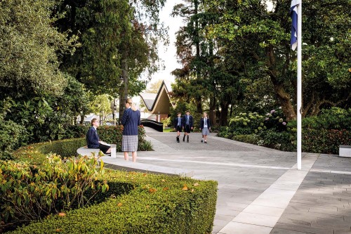 Students on campus grounds by flagpole.